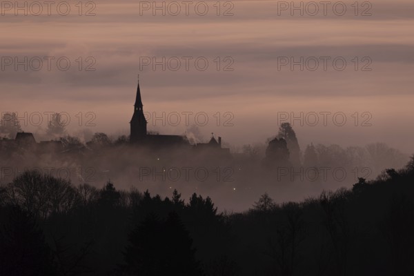 Wisps of mist drift into the town of Kronberg im Taunus in the morning shortly in front of sunrise.