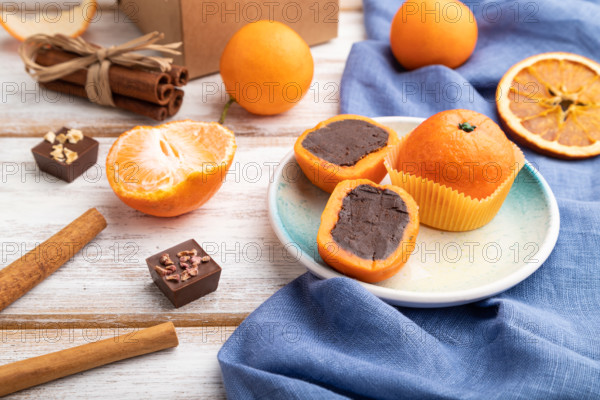 Truffle chocolate tangerine candies on a white wooden background and blue linen textile. Side view,