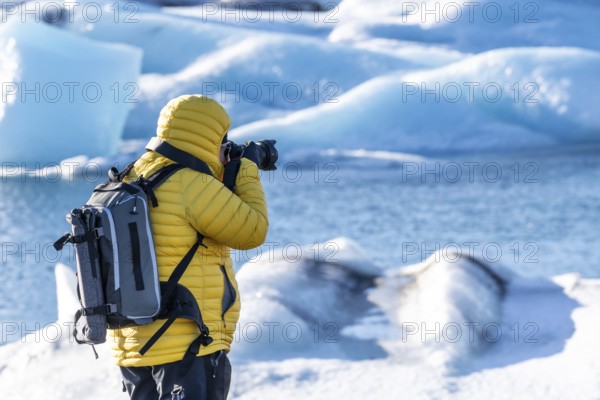 A photographer photographing the floating icebergs in the Jokulsarlon glacier lagoon in Iceland.