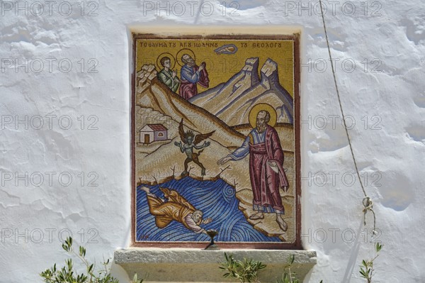 Mosaic depiction on a white wall showing a religious scene with several figures and mountains,