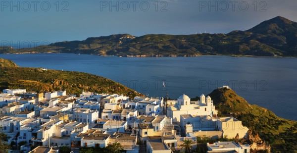 View of Plaka village on Milos island with traditional greek white houses on sunset. Plaka town,