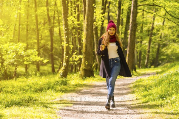 Latin girl with a black jacket, scarf and red woolen hat enjoying in an autumn park, walking along
