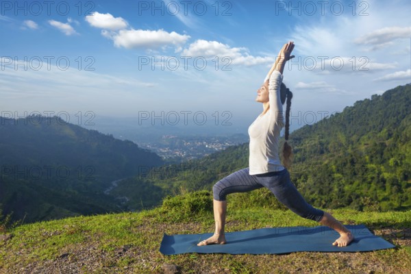 Yoga outdoors, sporty fit woman doing yoga asana Virabhadrasana 1, Warrior pose posture outdoors in