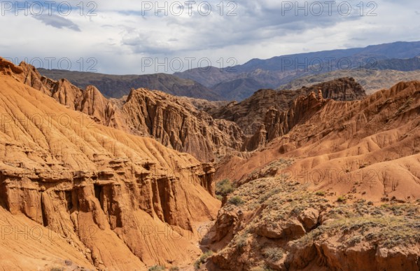 Eroded mountain landscape with sandstone cliffs, canyon with red and orange rock formations,
