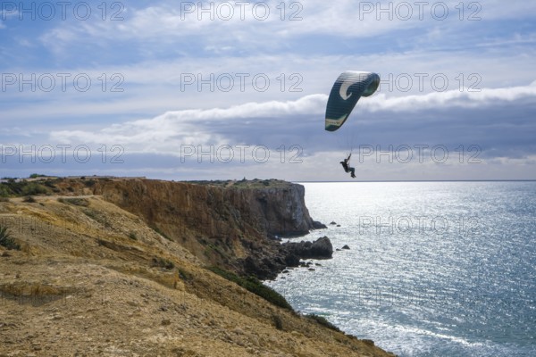 Sagres, Algarve, Portugal - Paraglider flying on the town beach Praia da Mareta, at the back left