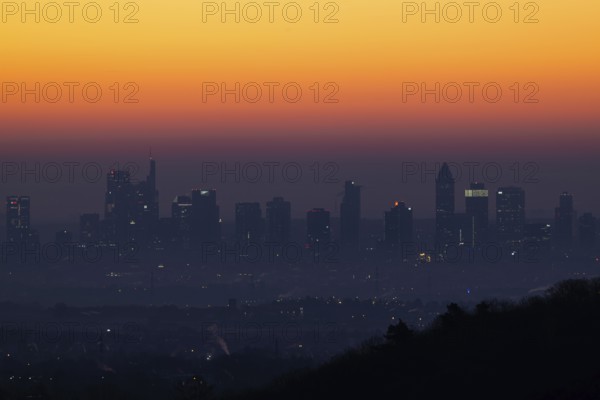 Shortly in front of sunrise, the sky behind the Frankfurt banking skyline turns yellow and orange,