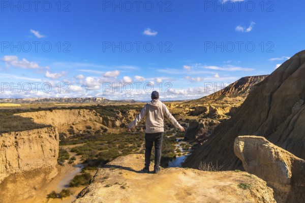 Tourist standing on a cliff with open arms, contemplating the breathtaking view of bardenas reales