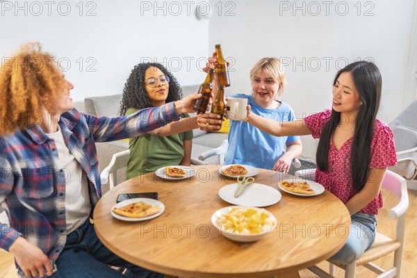 Four diverse friends are enjoying a meal together, toasting drinks and eating pizza at a round