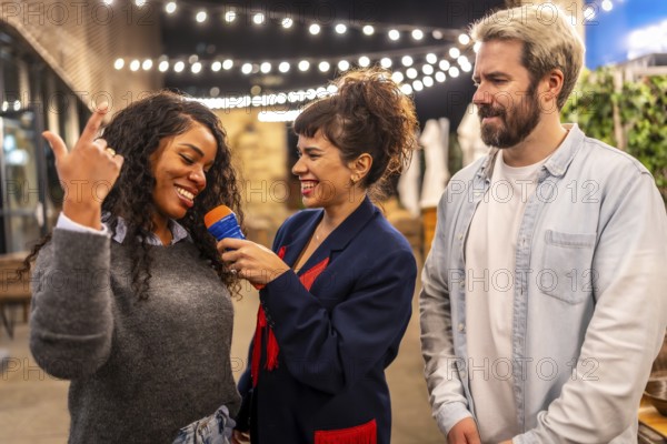 Multi-ethnic happy friends enjoying singing karaoke together at night outdoor party in the terrace
