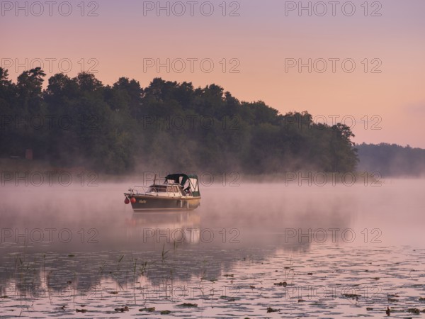 Morning atmosphere at Lake Grienerick, boat anchored, morning mist on the water, Rheinsberg,