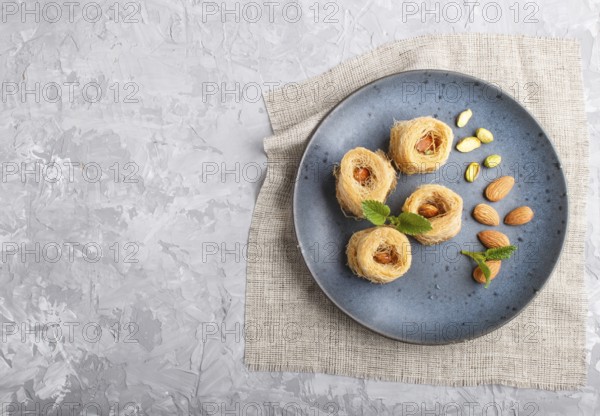 Kunafa, traditional arabic sweets in blue ceramic plate on a gray concrete background. top view,