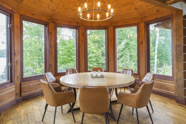 Round wooden dining table with tan leather armchairs in dining room inside a milled Eastern white