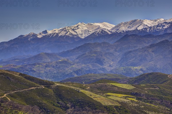 Mountain landscape with snow-covered peaks, green hills and windy paths, Lefka Ori, White