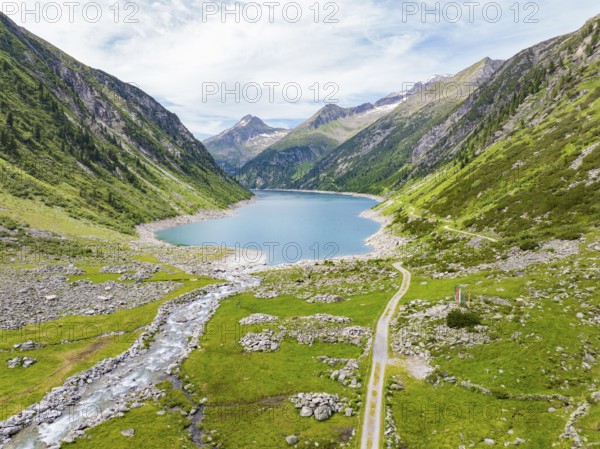 An idyllic mountain lake surrounded by high peaks and green meadows under a blue sky, Klein Tibet,