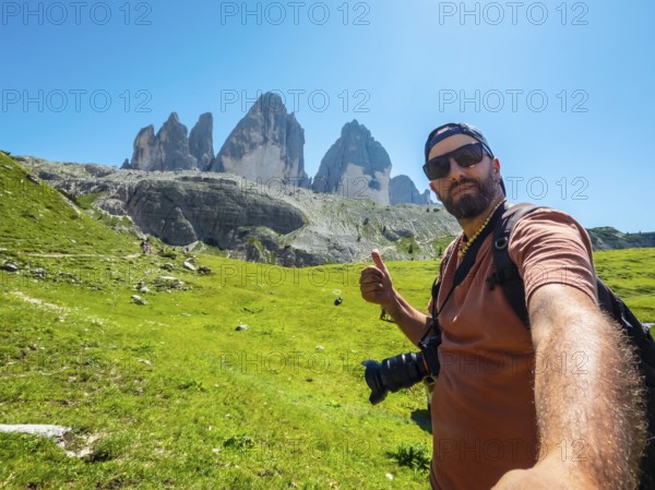 Photographer taking a selfie while hiking showing thumbs up sign with tre cime di lavaredo