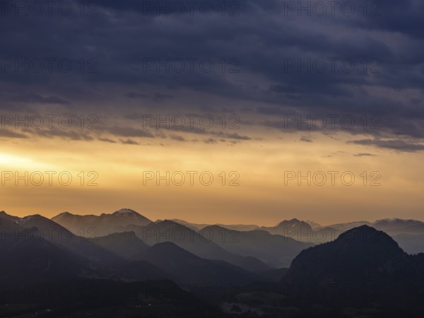 Alpine panorama under an overcast sky, illuminated by the sun through a gap in the clouds,