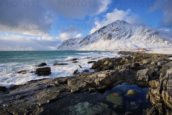 Beach of Norwegian sea on rocky coast in fjord on sunset in winter. Vareid beach, Lofoten islands,