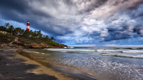Panorama of gathering storm on beach and Kovalam (Vizhinjam) lighthouse on stormy sunset. Kerala,