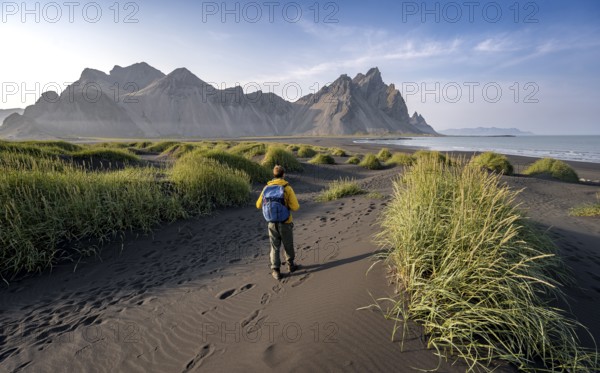 Tourist on a sand dune, Black beach with volcanic sand, Sand beach, Dunes with grass, Stokksnes