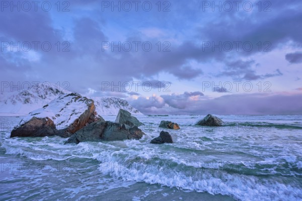 Waves of Norwegian sea on rocky coast in fjord on sunset with sun. Skagsanden beach, Lofoten