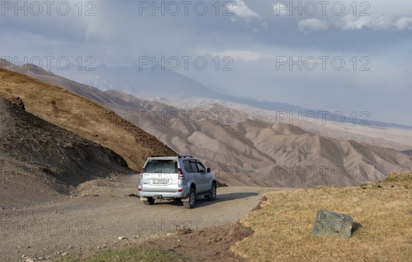 Off-road vehicle at the Tyibel Pass, mountain landscape of the Song Kul Too mountain range, Naryn