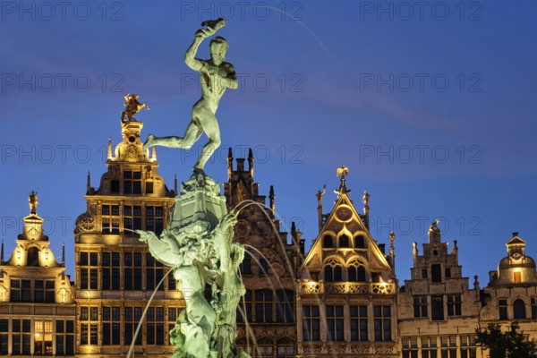 Antwerp famous Brabo statue and fountain on Grote Markt square illuminated at night and old houses.