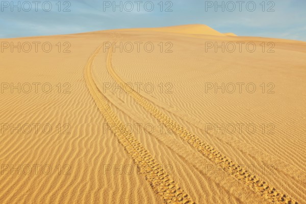 All-terrain vehicle (ATV) tracks in white sand dunes on sunrise, Mui Ne, Vietnam. Dunes around Bao