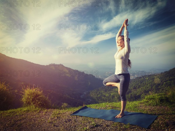 Yoga practice outdoors, woman practices balance yoga asana Vrikshasana tree pose in Himalayas