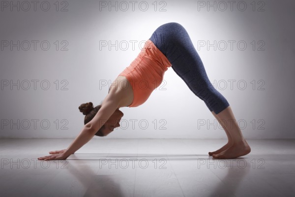 Beautiful sporty fit yogini woman practices yoga asana adhomukha svanasana, downward facing dog