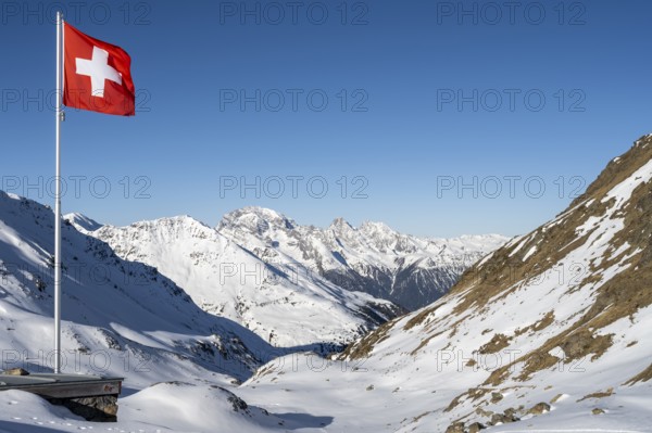 Swiss flag in front of mountain landscape in winter, mountain panorama with the peaks of the