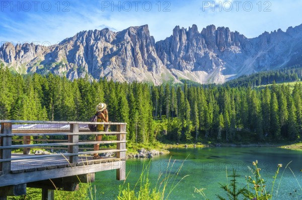 Female tourist admiring the stunning landscape of lake carezza with the latemar massif in the