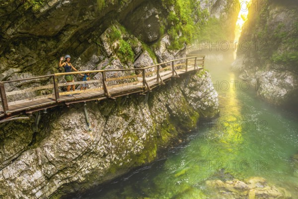 Tourists enjoying a scenic walk along the wooden pathway above the emerald radovna river,