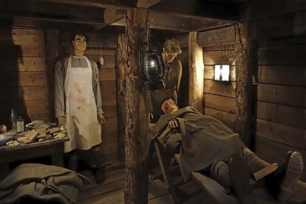 Diorama of WWI British almoner and doctor treating wounded soldier in dugout of WW1 trench at