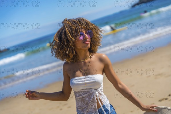 Happy brunette beauty woman wearing summer clothes, sunglasses and holding a sun hat on hand