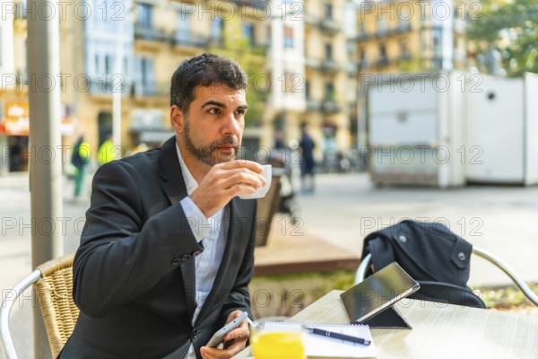 Businessman enjoying morning coffee while working with smartphone and digital tablet in an outdoor