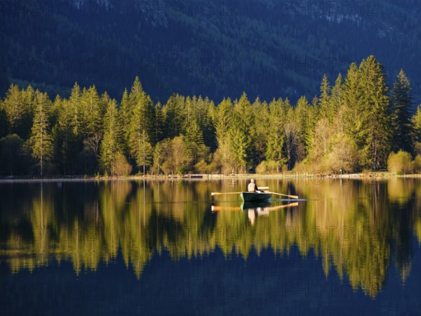 Angler in a rowing boat on the Hintersee in the first sunlight, Berchtesgaden National Park,