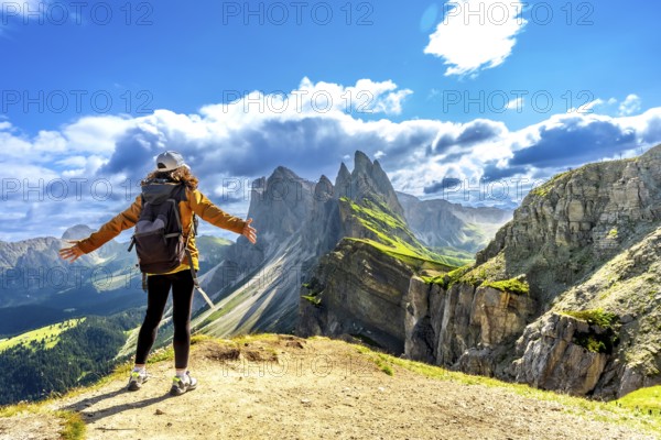 Hiker with open arms enjoying the breathtaking view of the odle mountains in seceda, dolomites,