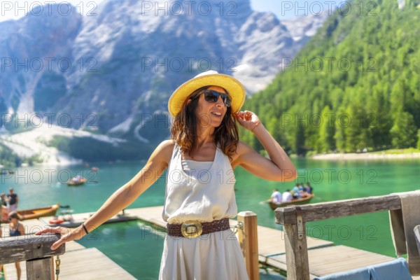 Fashionable tourist wearing sunglasses and straw hat enjoying summer at lake braies, also called