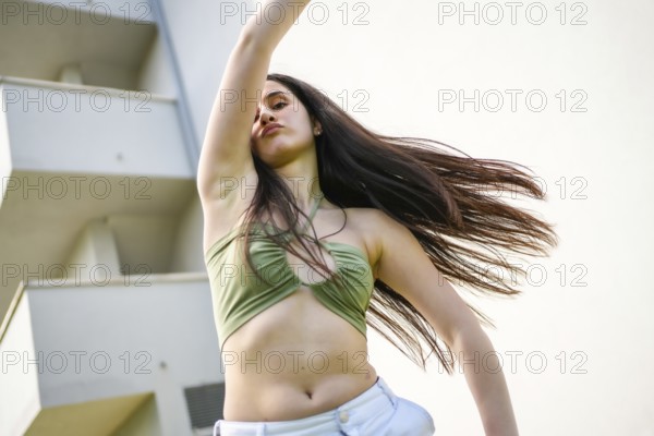 Low angle view motion photo of a caucasian young woman dancing energetically raising arm in the