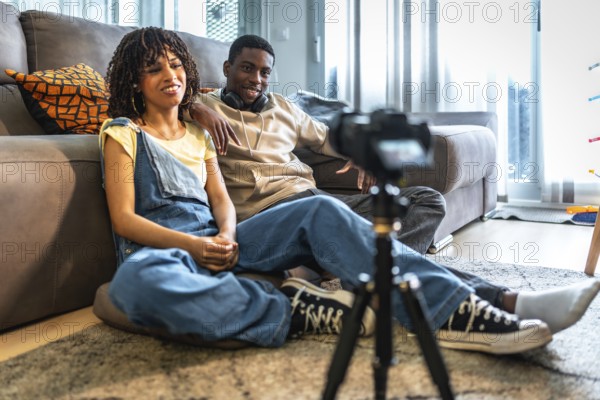 Two influencers are recording a vlog in their living room, creating engaging content for their