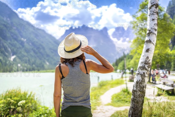 Woman wearing straw hat enjoying the view of the beautiful lago di landro with the dolomites in the