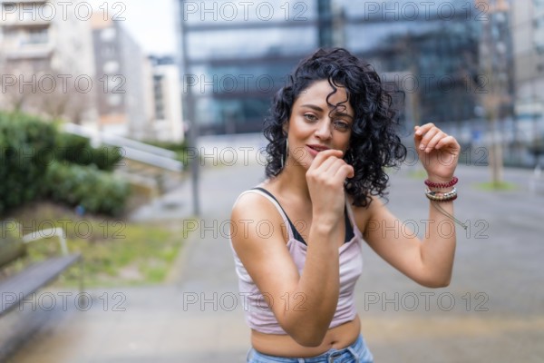 Stylish young woman with curly hair enjoying dancing outdoors, showcasing urban lifestyle and