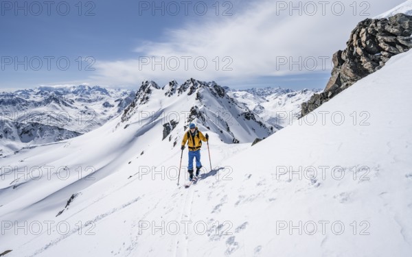 Ski tourer on a mountain ridge, mountain landscape with snow, mountain panorama with summit of the
