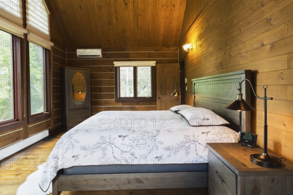 King size bed on wood-frame with wooden headboard, nightstand with antique industrial style lamp,