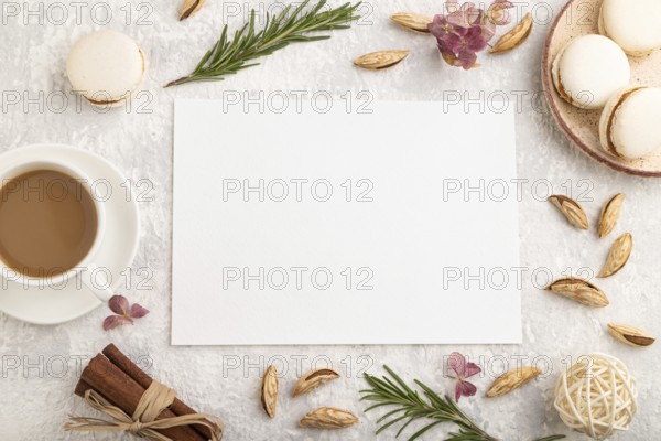 White paper sheet mockup with cup of coffee, almonds and macaroons on gray concrete background.