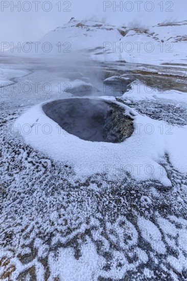 Hot springs and geothermal area in front of a mountain landscape in winter, cloudy mood, Hverir,