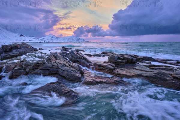 Waves of Norwegian sea on rocky coast in fjord on sunset with sun. Skagsanden beach, Lofoten