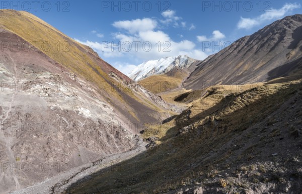 Valley with mountain stream between high mountains in autumn, mountain landscape with glaciated
