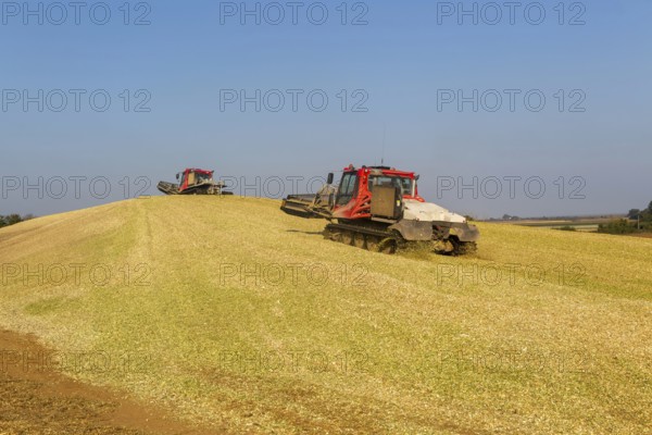 Piston Bully tracked bulldozer vehicles building silage clamp of sweetcorn maize in field stored