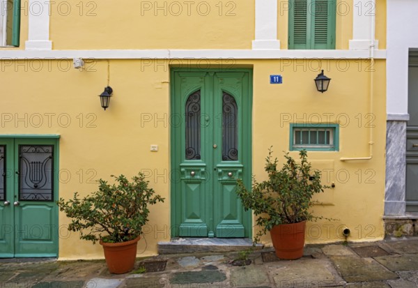 A charming house with a yellow facade and green doors in the Plaka district of Athens, Greece,